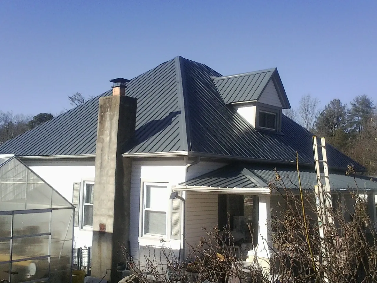Dark blue standing seam metal roof on a white farmhouse with dormer — Slate & Tile Roof Repair by Roofing Brothers in Robertsville