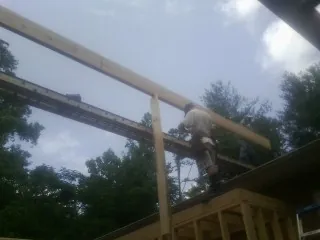 Carpenter setting a ridge beam over a new addition frame — Ice Dam Removal by Roofing Brothers in Robertsville