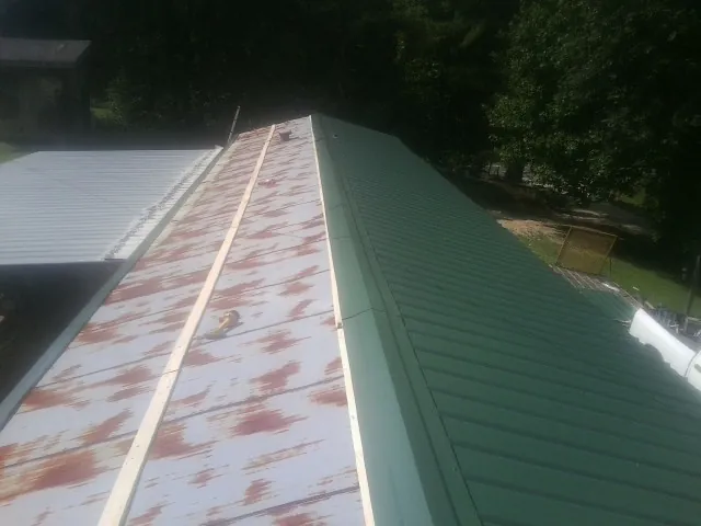 Old rusted panels beside newly installed green metal roofing — Wind Damage Roof Repair by Roofing Brothers in Robertsville