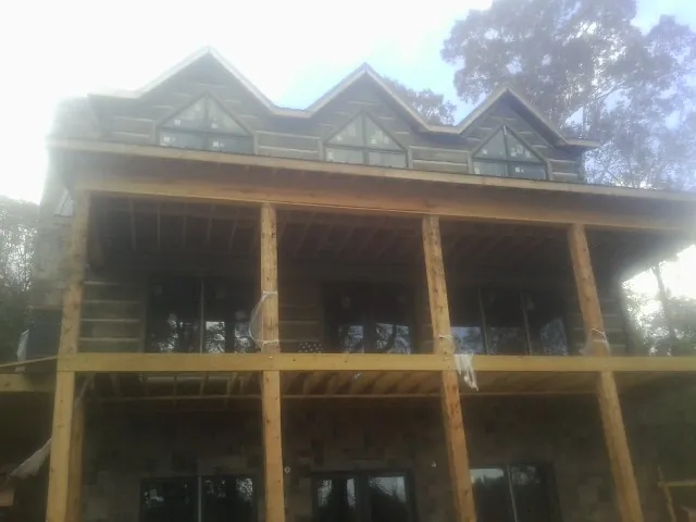 Dormers and porch framing on a large log home under construction — Roof Coating work by our crew in Robertsville