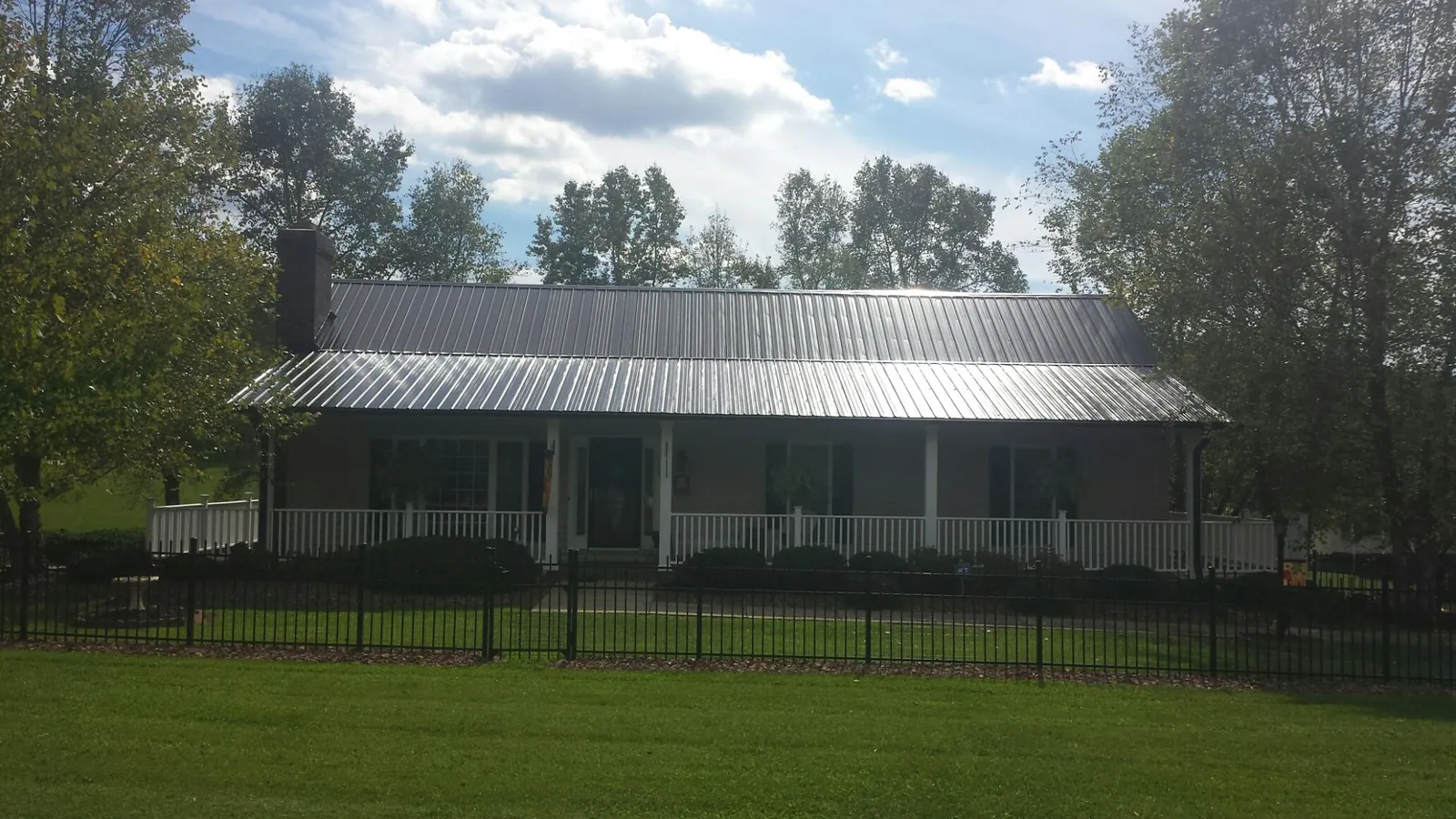 Gray metal roof on a brick ranch with a full width front porch — Gutter Guard Installation work by our crew in Robertsville