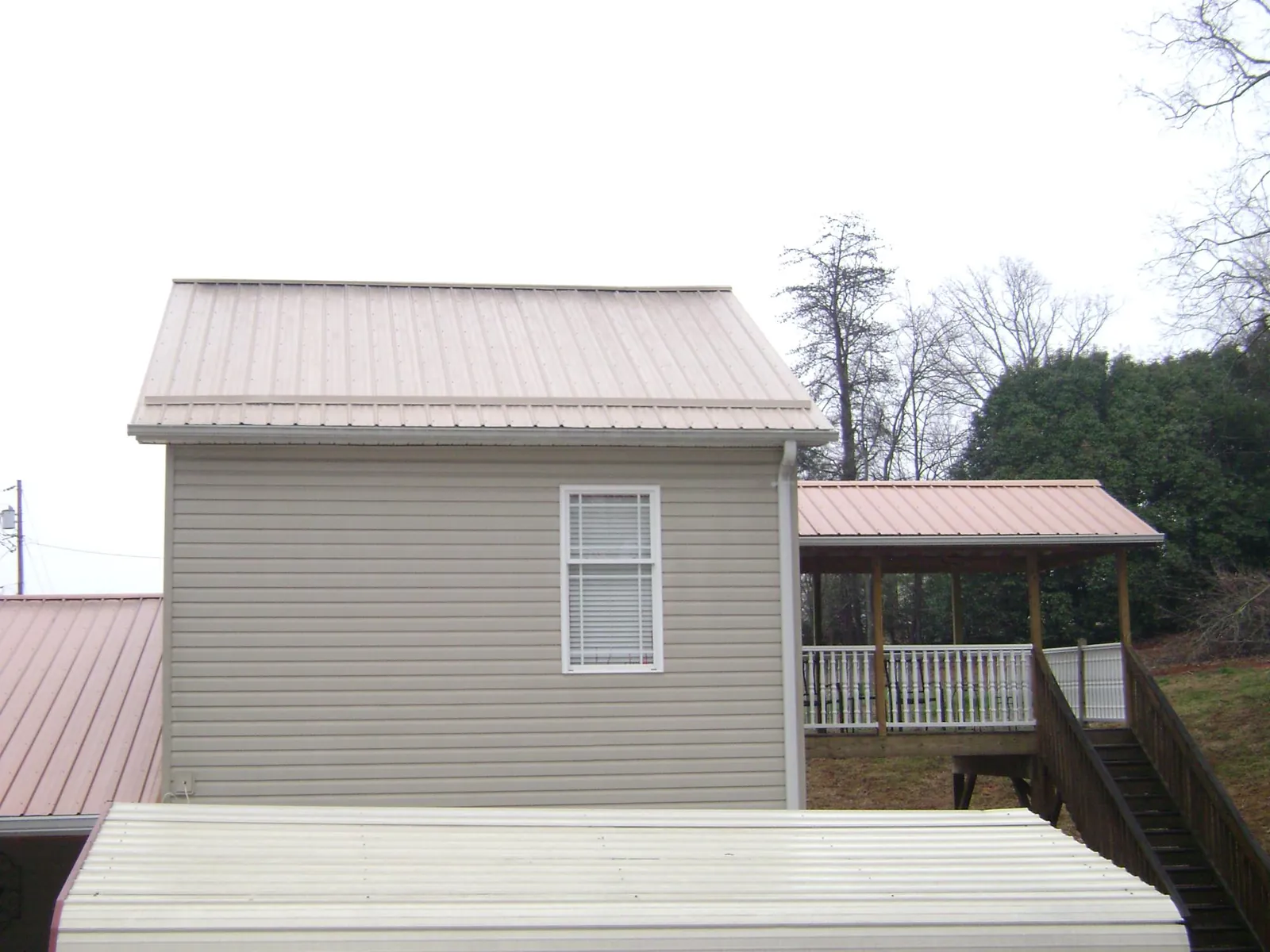 Tan metal roofs on a two story addition and attached porch, from a Roof Replacement job in Robertsville