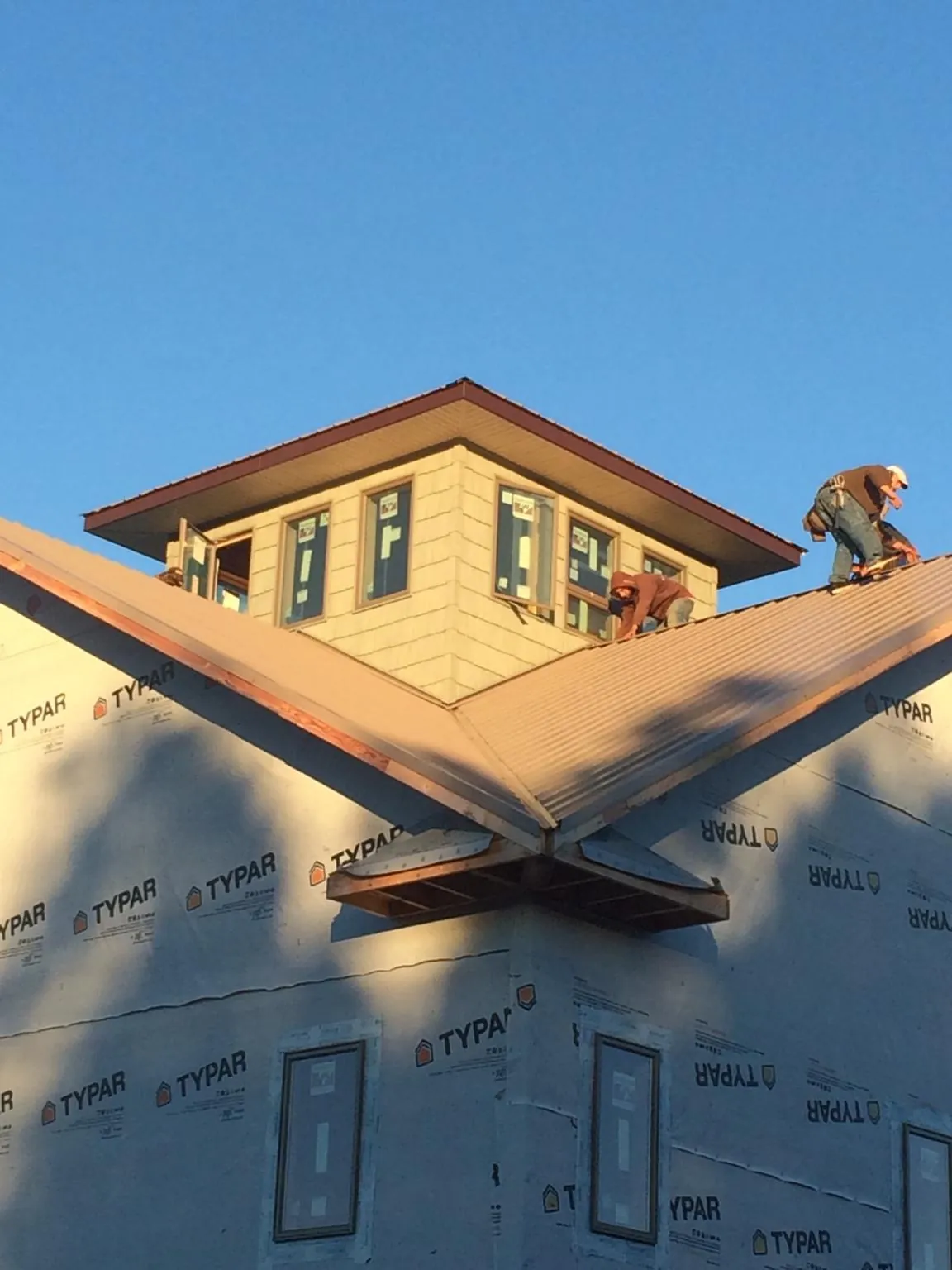 Roofers working around a rooftop cupola on a new metal roof at sunset — Roof Waterproofing in Robertsville by Roofing Brothers